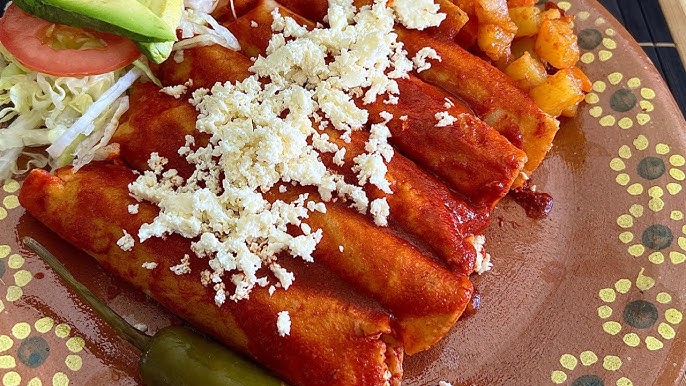 Enchiladas rojas tradicionales bañadas en salsa casera con crema, queso fresco y cebolla morada